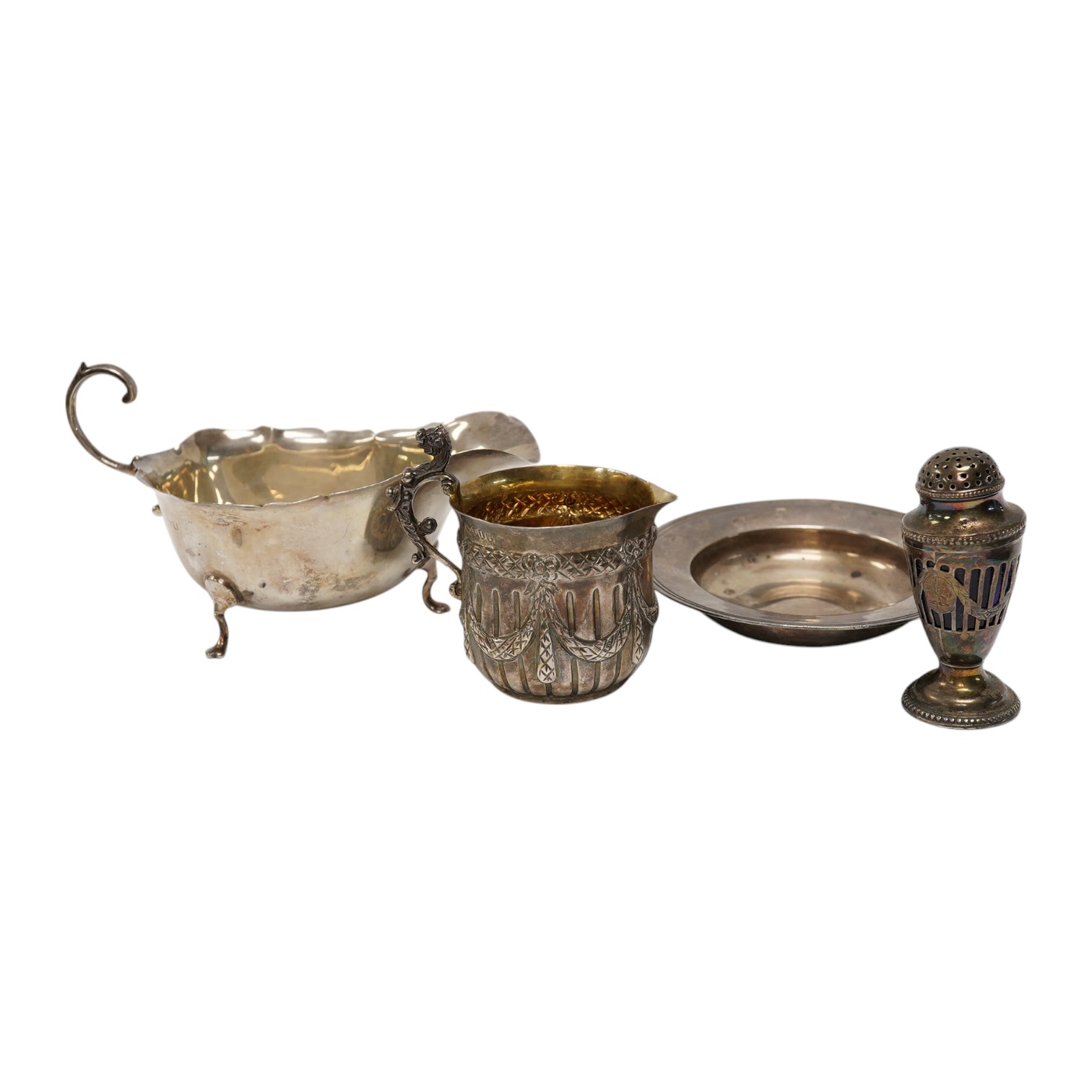 A Victorian silver cream jug, maker JR, London, 1884, together with a later silver sauce boat, pepperette and dish. Condition - poor to fair